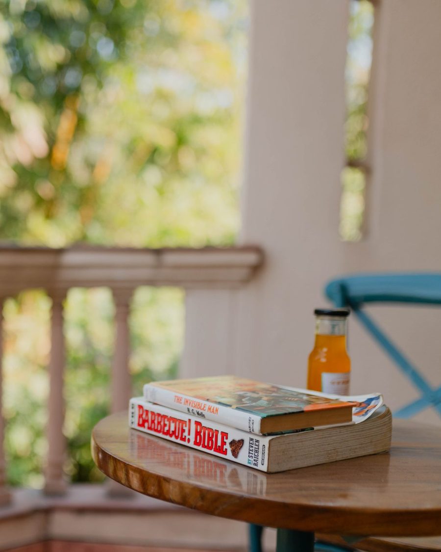 Rincón cálido de lectura en un balcón, con libros y luz natural, evocando calma y acompañamiento